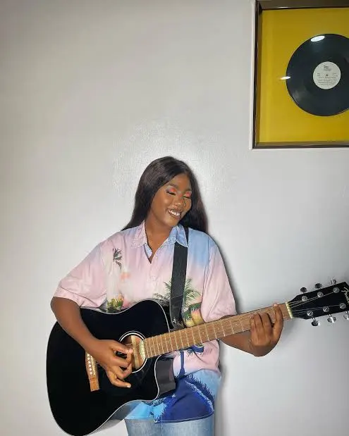 Favour Ojo with guitar, seated